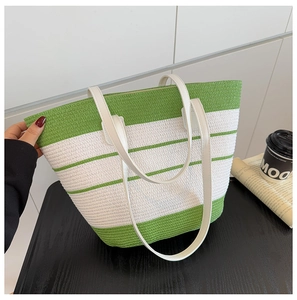Détail du sac cabas tissé vert et beige avec poignée en similicuir sur une table