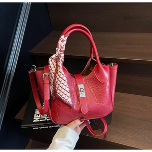Detail of red croc-embossed bucket bag with silver metal twist lock and silk scarf handle