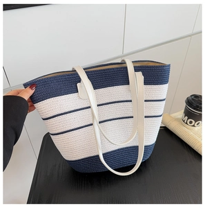 Détail du sac de plage tressé rayé bleu marine et blanc avec des anses en similicuir blanc