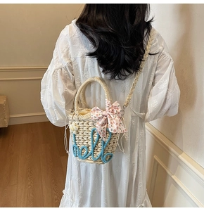 Detail of straw bucket bag with blue hello embroidery and floral bow decoration