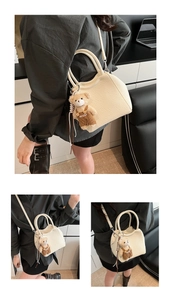 Détail du sac seau en cuir grainé blanc crème avec un joli pendentif ours en peluche