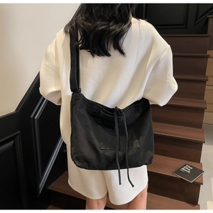 Close-up of black canvas tote bag with drawstring closure and square front pocket detail