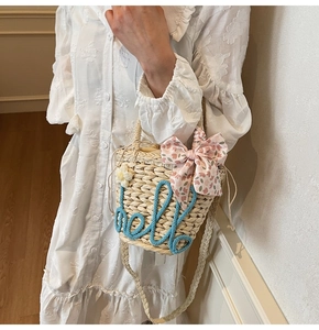 Detail of handmade straw bucket bag with floral ribbon and embroidered hello text