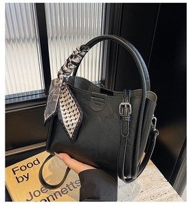 Détail du sac seau noir avec gaufrage fashion bags et foulard en soie imprimé sur l'anse