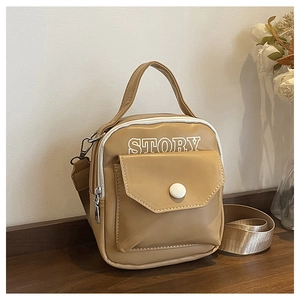 Détail d'un mini sac bandoulière en cuir marron avec logo STORY sur bois