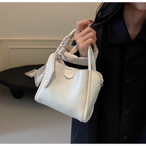 Detail of off-white leather bucket bag with silk scarf handle and magnetic snap closure
