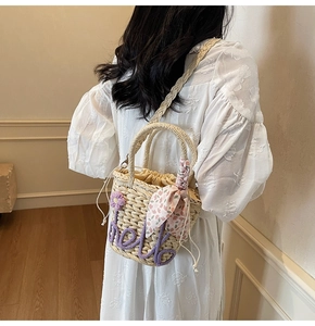 Detail of straw bucket bag with hello embroidery and floral scarf wrapped on handle