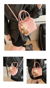 Détail d'un sac seau en cuir rose avec charm ourson et bandoulière amovible pour femmes