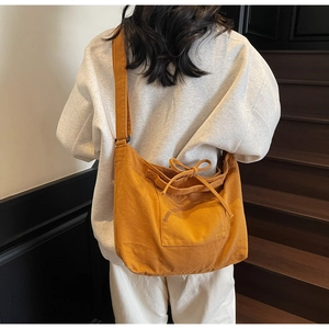 Detail of ginger yellow large canvas tote bag with decorative drawstring bow on model