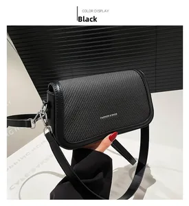 Detail of black woven texture flap and silver metal buckle on elegant shoulder bag