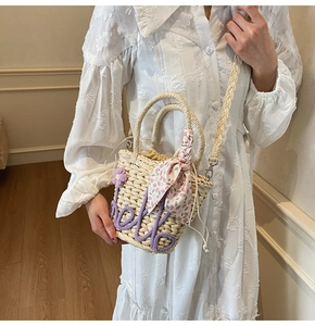 Detail of handmade straw bucket bag with purple letter weaving and floral silk scarf charm