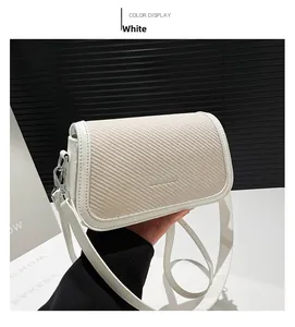 Detail of white crossbody bag featuring a textured woven flap and silver metallic hardware