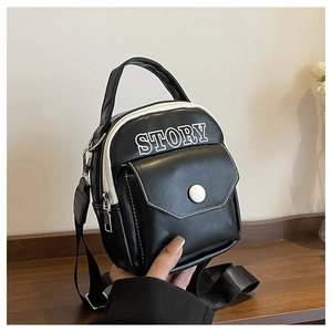 Détail d'un mini sac bandoulière noir avec coutures blanches et logo STORY imprimé