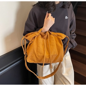 Detail view of large ginger yellow canvas tote bag with adjustable shoulder strap and pocket