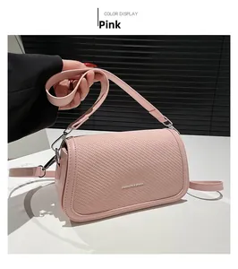 Detail of pink leather crossbody bag featuring a woven textured flap and white lettering