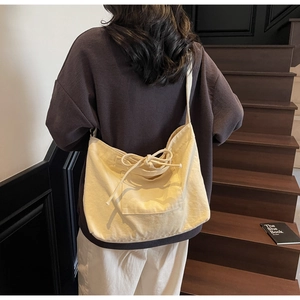 Close-up of beige canvas tote bag featuring a decorative bow and spacious front pocket