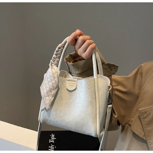 Close-up of cream white bucket bag with pleated handle and elegant checkered scarf detail