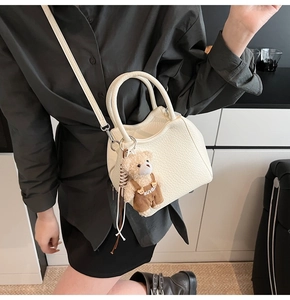 Détail du sac à bandoulière blanc texture litchi avec breloque ours en peluche mignon