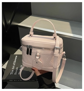 Close-up of pink box-style handbag with quilted diamond pattern and silver metal hardware