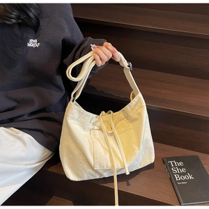 Detail of cream canvas tote bag showing drawstring closure and adjustable shoulder strap