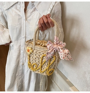 Detail of straw handbag featuring yellow hello embroidery and floral silk scarf handle