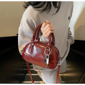 Détail du sac Boston rouge foncé montrant la texture vernie et l'ornement argenté