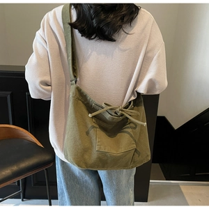Detail view of military green canvas crossbody tote with decorative bow and outer pocket