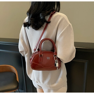 Détail du sac Boston en cuir brillant rouge foncé avec fermoir en métal et bandoulière
