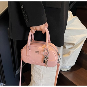 Détail du sac Boston en cuir verni rose avec logo métallique et pendentif cadenas chic