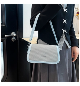 Detail showing the woven texture panel and black Fashion Bag print on a blue shoulder bag