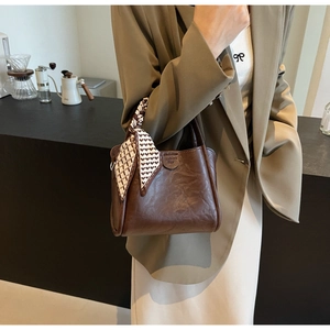 Detail of dark brown bucket bag with wrinkled texture and printed silk scarf handle