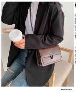 Brown retro chain bag styled with a casual black blazer and jeans in an urban setting