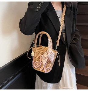 Close-up of handmade straw bucket bag with pink hello embroidery and floral silk scarf detail