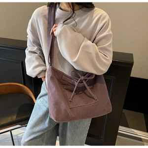 Detail view of purple canvas tote bag with decorative bow and functional front pocket