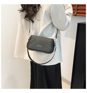 Chic black crossbody bag with carbon fiber texture worn with a white blazer