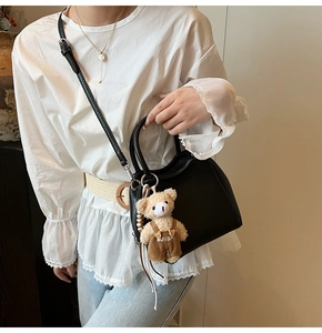 Vue détaillée du sac seau noir en cuir litchi avec son charmant ours en peluche