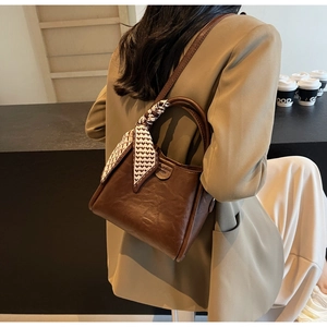 Detail of dark brown leather bucket bag with geometric silk scarf wrapped handle décor