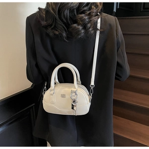 Détail d'un sac Boston blanc crème avec ferrures argentées et bandoulière en cuir réglable