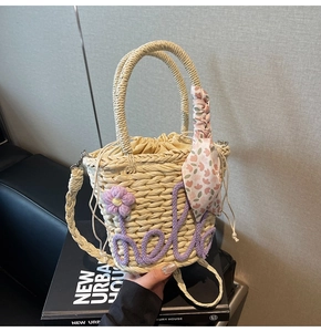Detail of woven straw bucket bag with purple Hello embroidery and floral scarf handle