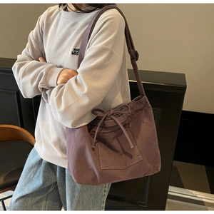 Detail of purple canvas hobo bag featuring drawstring bow pocket and wide strap