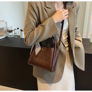 Detail of dark brown lychee leather bucket bag with decorative silk scarf and strap