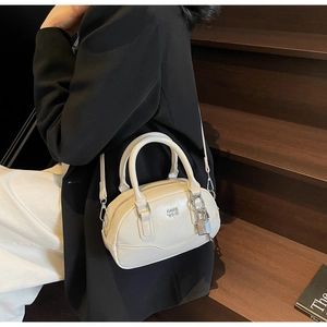 Vue détaillée du sac Boston crème avec logo porté par un mannequin au style minimaliste