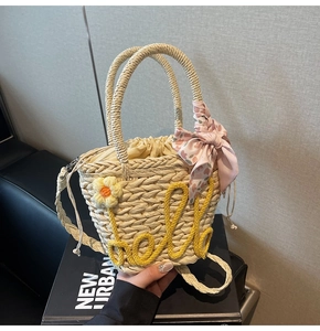 Detail of hand-woven bucket bag with yellow hello embroidery and floral silk scarf charm