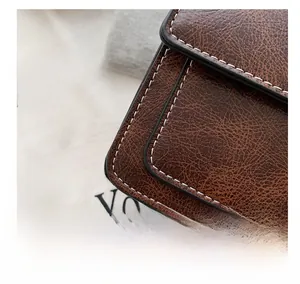 Detail shot of brown vintage leather bag with white decorative stitching and grain texture