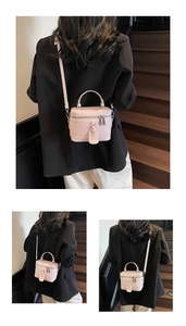Detailed view of pale pink quilted box bag with top handle and detachable strap on a model