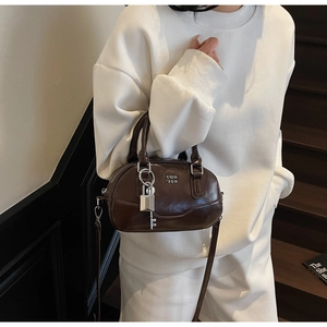 Détail du sac Boston marron foncé avec serrure argentée et bandoulière réglable