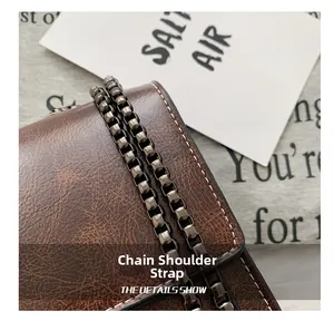 Detail shot of the vintage brown PU leather bag with metallic chain and white stitching
