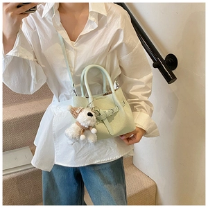 Détail du sac à main vert menthe texturé avec un pendentif peluche chien porte-bonheur