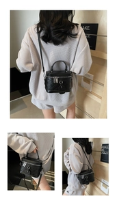 Detail view of black quilted leather bucket bag with top handle and metal dual zippers