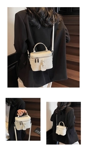 Detail view of white quilted vanity bag with metal zipper and adjustable strap
